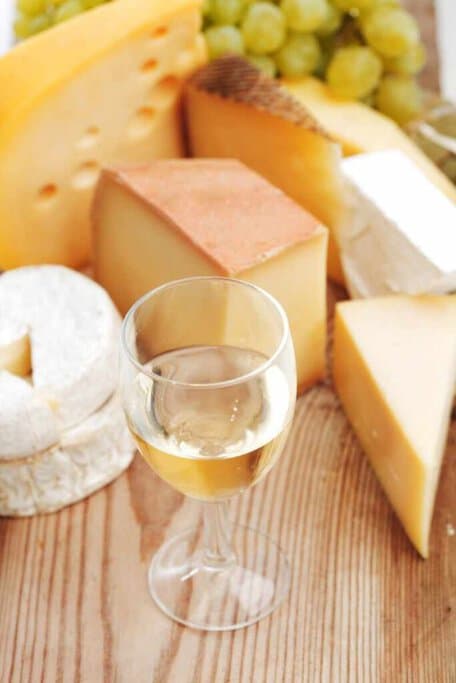 An assortment of artisanal cheeses paired with a glass of white wine, capturing the culinary delights encountered on wine tours from Sydney to Hunter Valley.