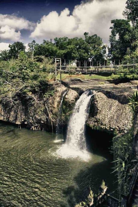 Scenic waterfall flowing into a pool in the lush Daintree Forest in Queensland, highlighting a natural wonder featured in many travel deals in Australia.
