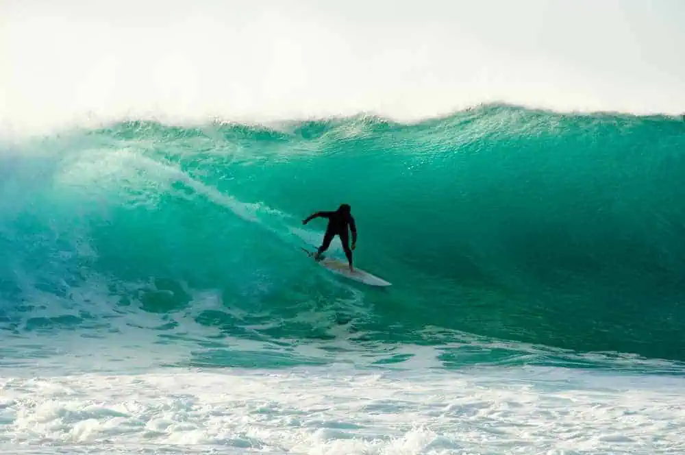 Surfer riding a towering wave in Margaret River, showcasing the thrilling water sports available, even in the winter season, for those seeking adventure.