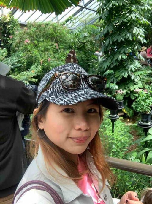 A woman smiling with a butterfly perched on her hat inside the Butterfly House at Melbourne Zoo. This serene and vibrant setting is one of Melbourne's most Instagrammable places, offering visitors the chance to capture unique and colourful photos with beautiful butterflies and lush greenery.