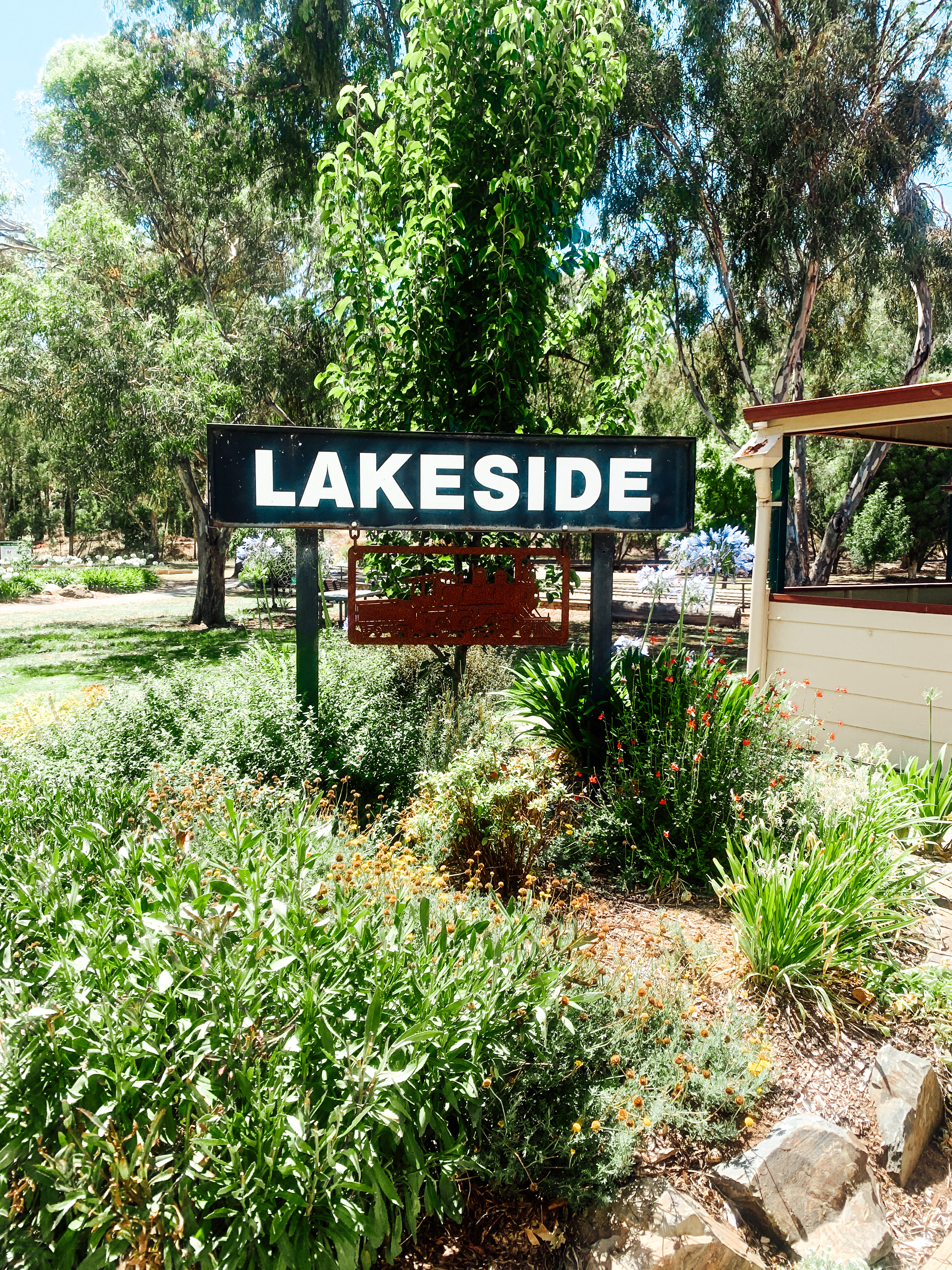 The 'LAKESIDE' sign amidst lush greenery at a peaceful garden in Clare Valley Model Engineers, inviting visitors to explore the tranquil surroundings as one of the relaxing things to do in Clare Valley.