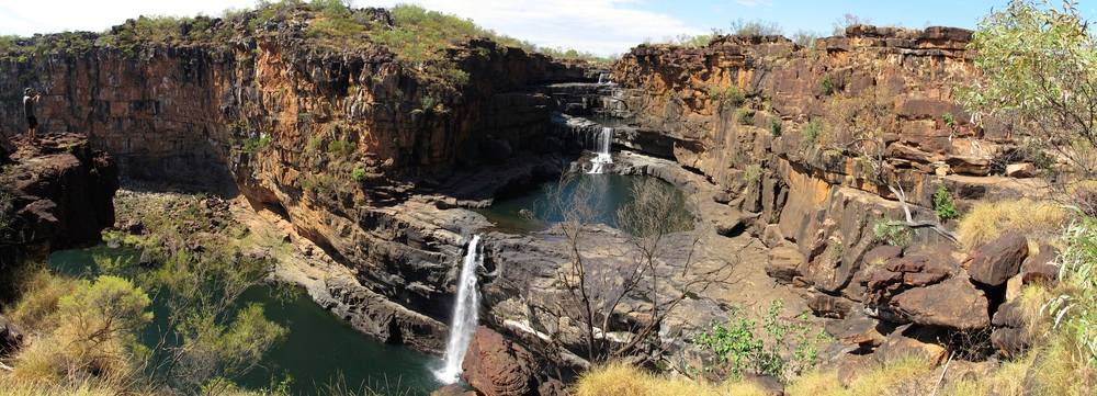 Mitchell Falls in the Kimberley region of Western Australia, featuring multiple tiers of cascading water set against rugged red rock cliffs, exemplifying the dramatic landscapes of waterfalls in Australia and their allure for adventurous travellers.
