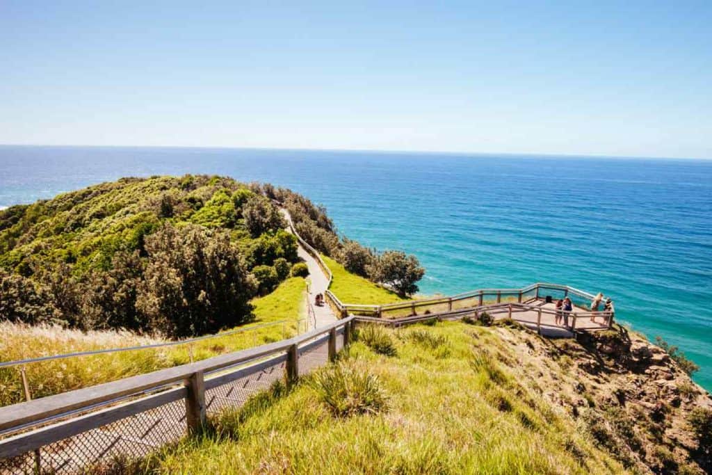 Scenic pathway near Cape Byron Lighthouse, surrounded by lush greenery and overlooking the sparkling blue ocean. This image captures the serene beauty of the walking trails, a highlight for visitors exploring the area.