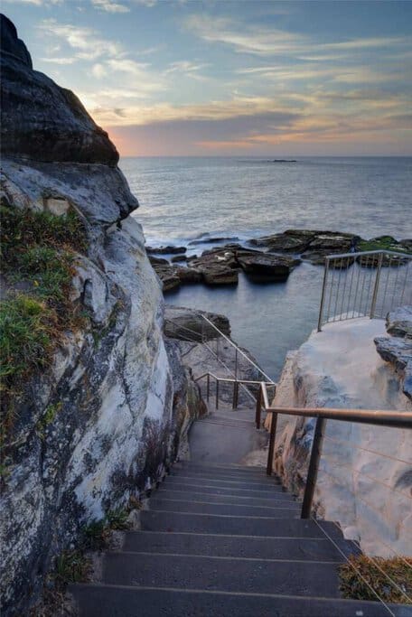 Rockpool access at Coogee Beach in Sydney, Australia, with a staircase leading down to rocky waters. Despite its appeal, Coogee Beach has been labelled one of Australia’s worst swimming spots due to unpredictable waves and occasional hazardous conditions.