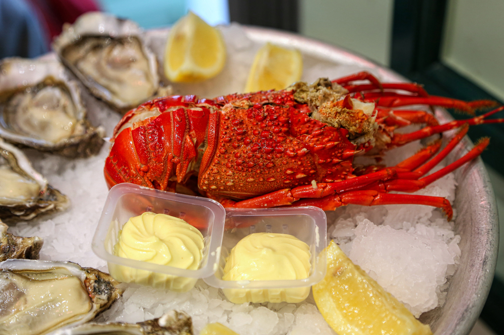 Closeup of Large dish with fresh seafood, lobster with oysters with lemon and sauce on ice in a restaurant
